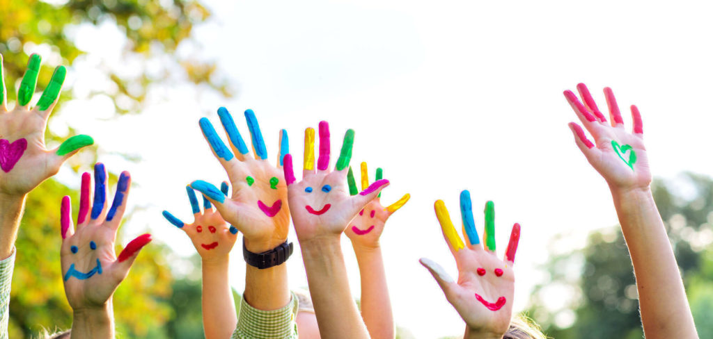 Des mains d'enfants coloriées et levées, connotant la prise en charge d'enfants par votre chauffeur VTC.
